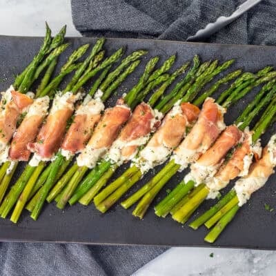Tray with prosciutto wrapped asparagus bunches lined up.
