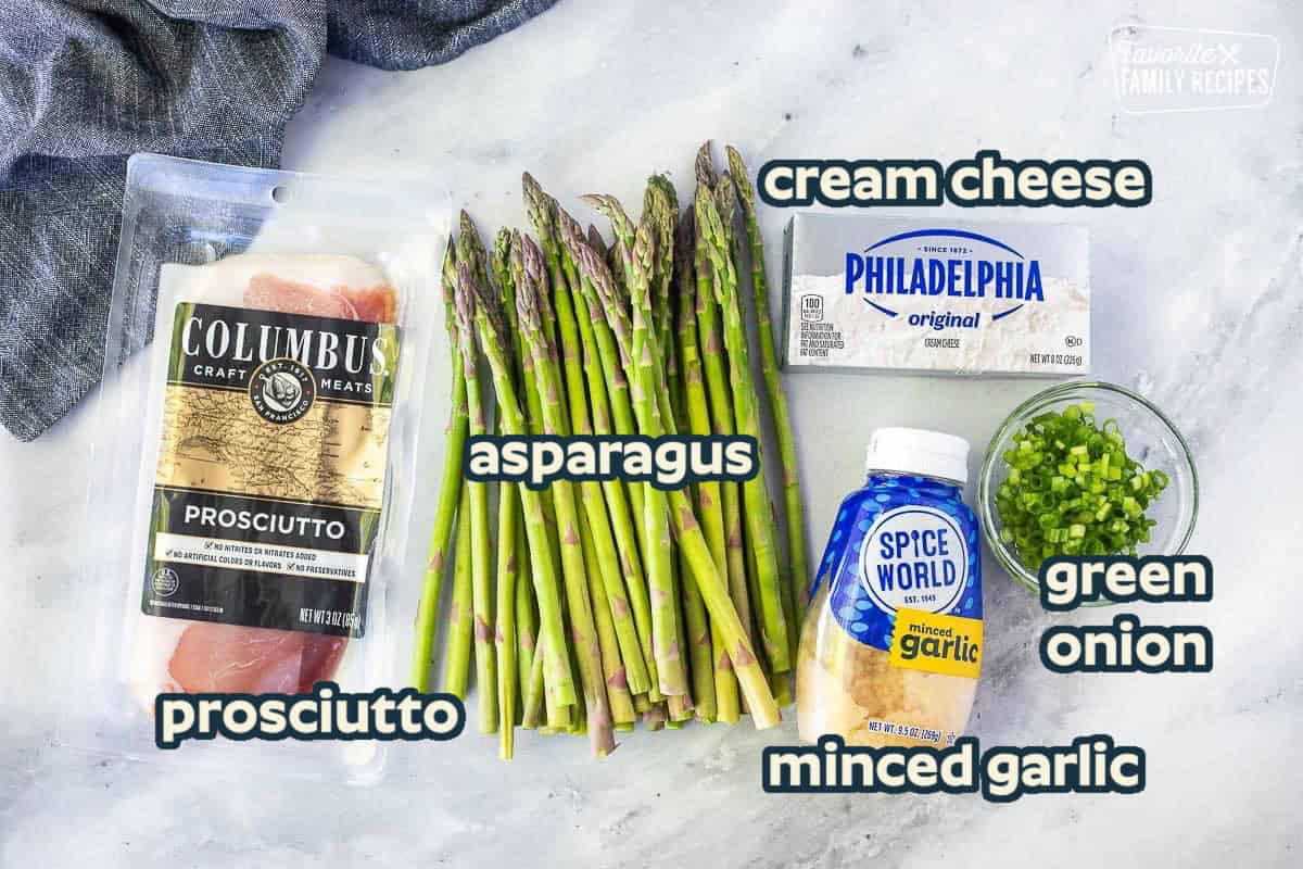 Ingredients to make prosciutto wrapped asparagus including asparagus, garlic, cream cheese, green onion and prosciutto.