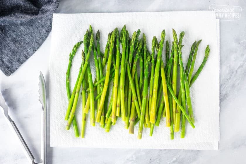 Asparagus on paper towels with tongs on the side.