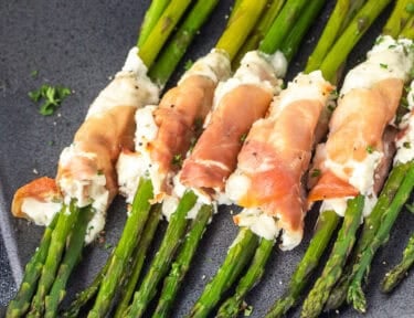 Tray with prosciutto wrapped asparagus bunches lined up.