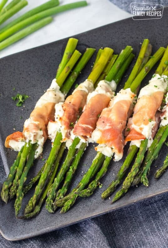 Tray with prosciutto wrapped asparagus bunches lined up.