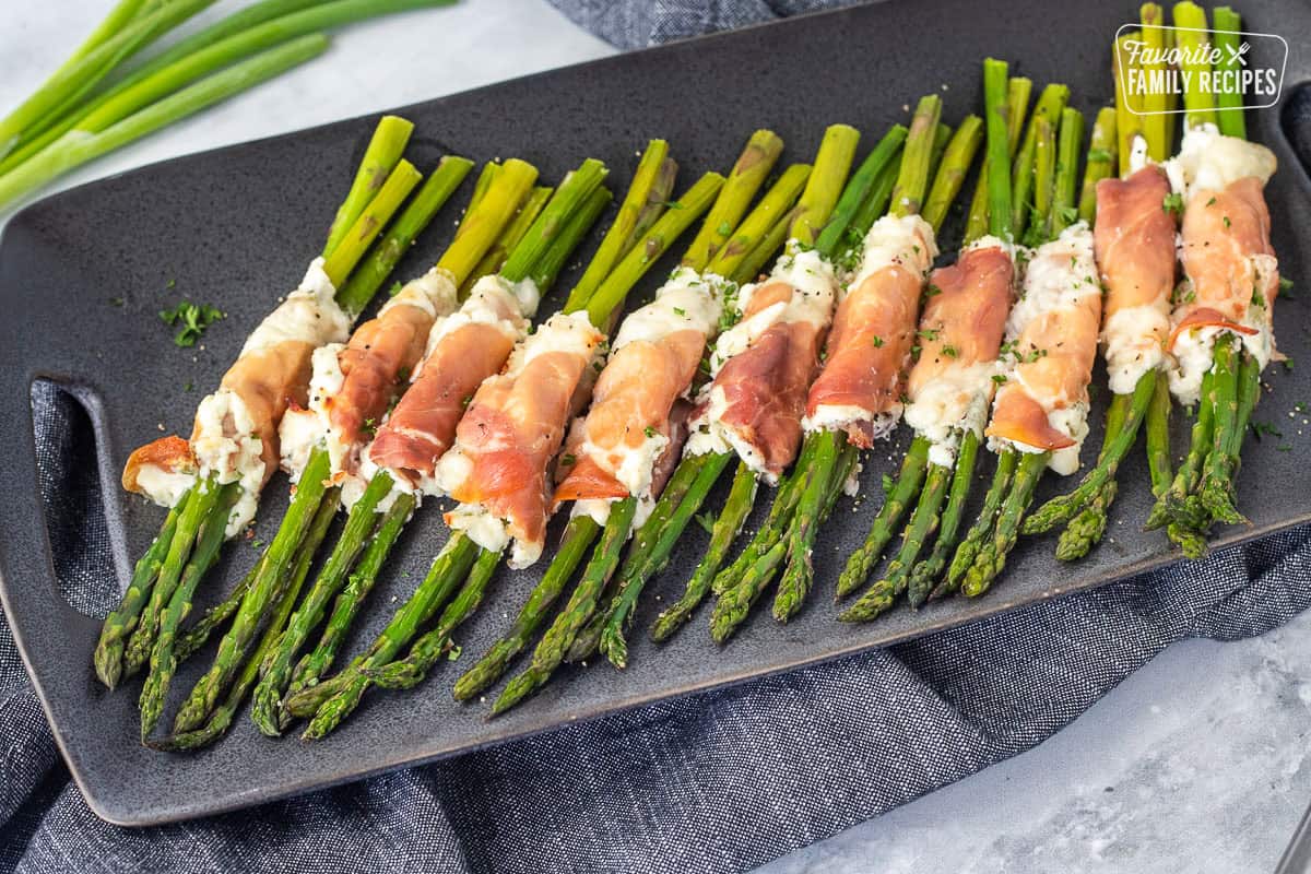 Tray with prosciutto wrapped asparagus bunches lined up.