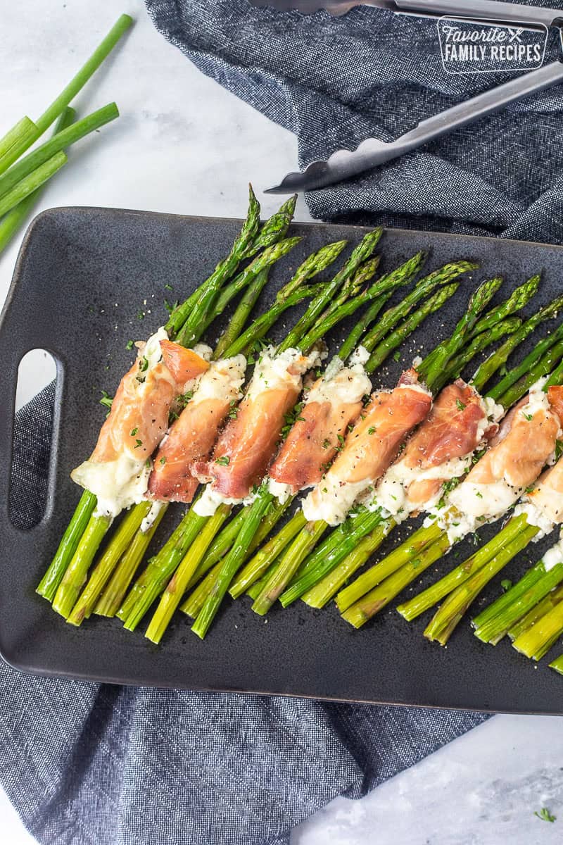 Tray with prosciutto wrapped asparagus bunches lined up.
