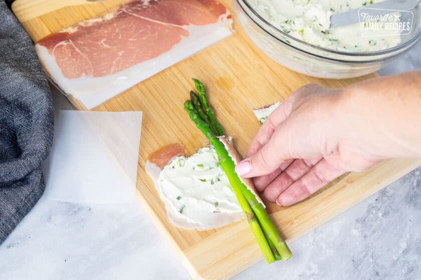 Wrapping prosciutto around three spears of asparagus.