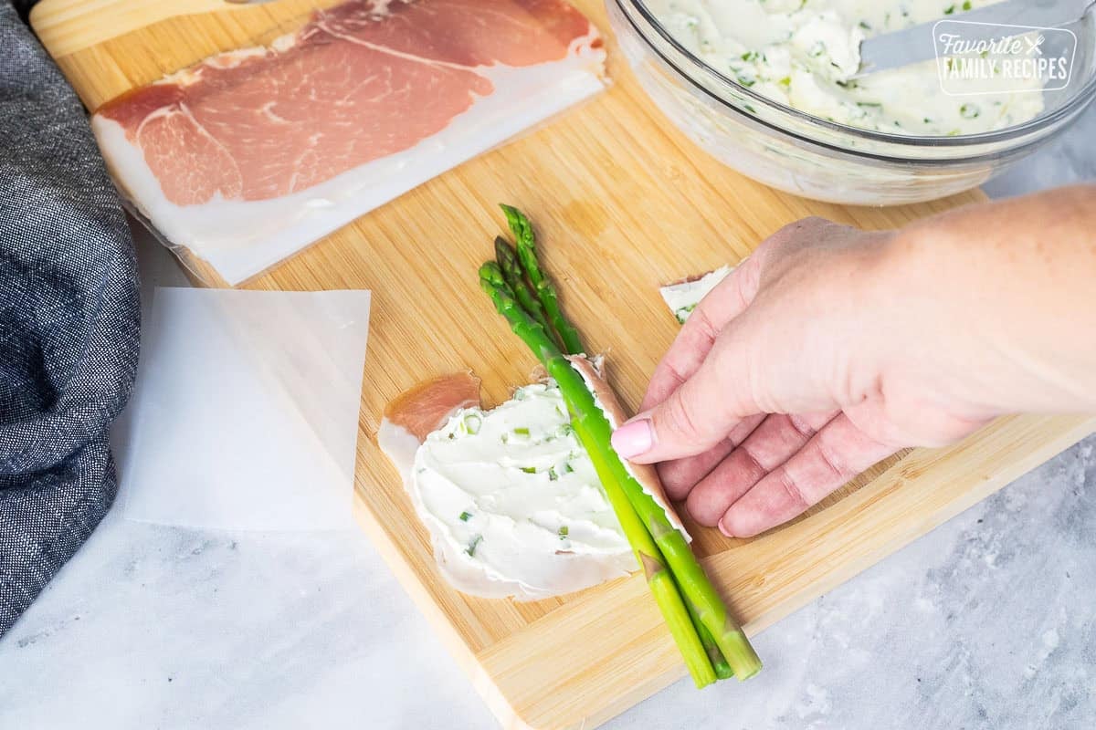 Wrapping prosciutto around three spears of asparagus.