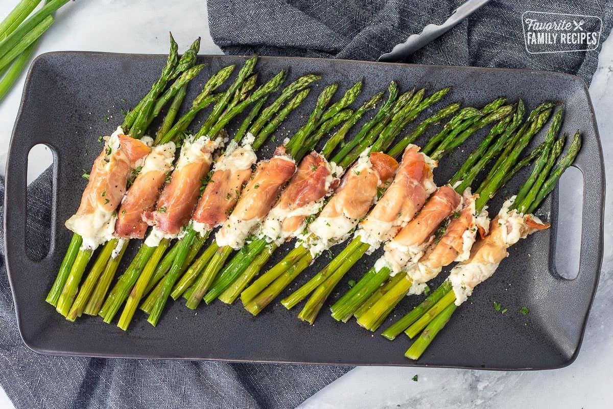 Tray with prosciutto wrapped asparagus bunches lined up.