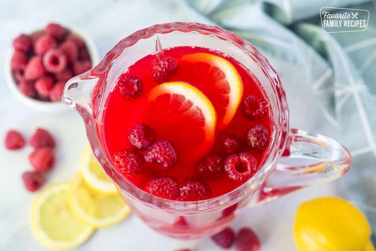 Pitcher of raspberry cordial with lemon slices and fresh raspberries.