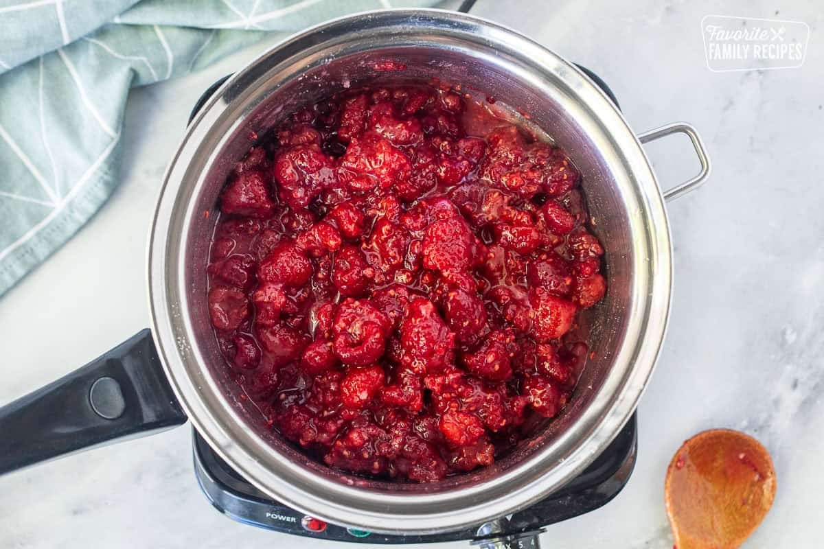 Saucepan with combined raspberries and sugar.