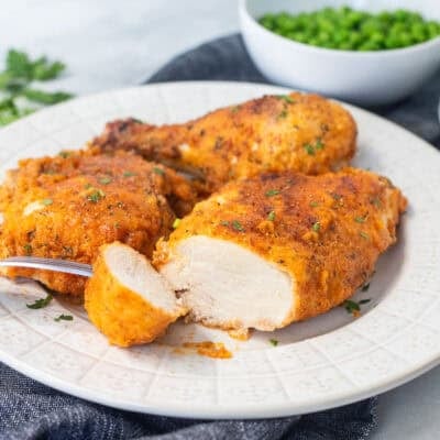 Cut piece of shake and bake chicken on a plate.