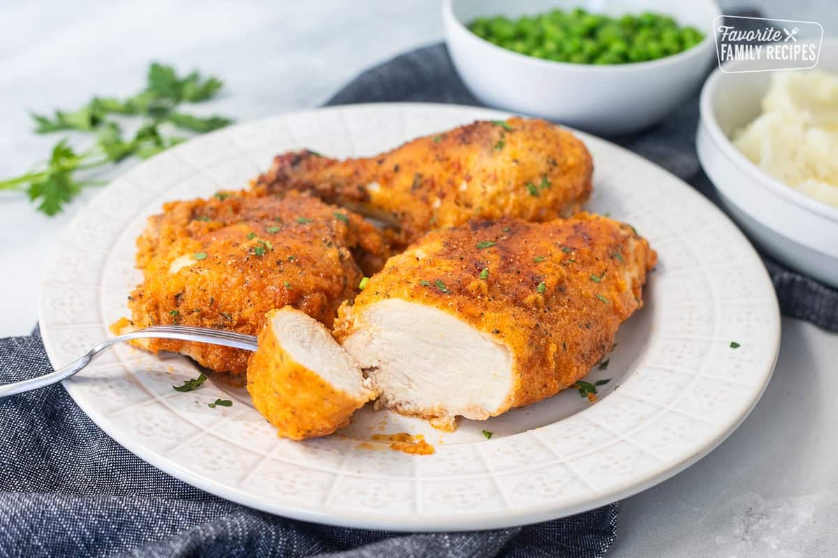 Cut piece of shake and bake chicken on a plate.