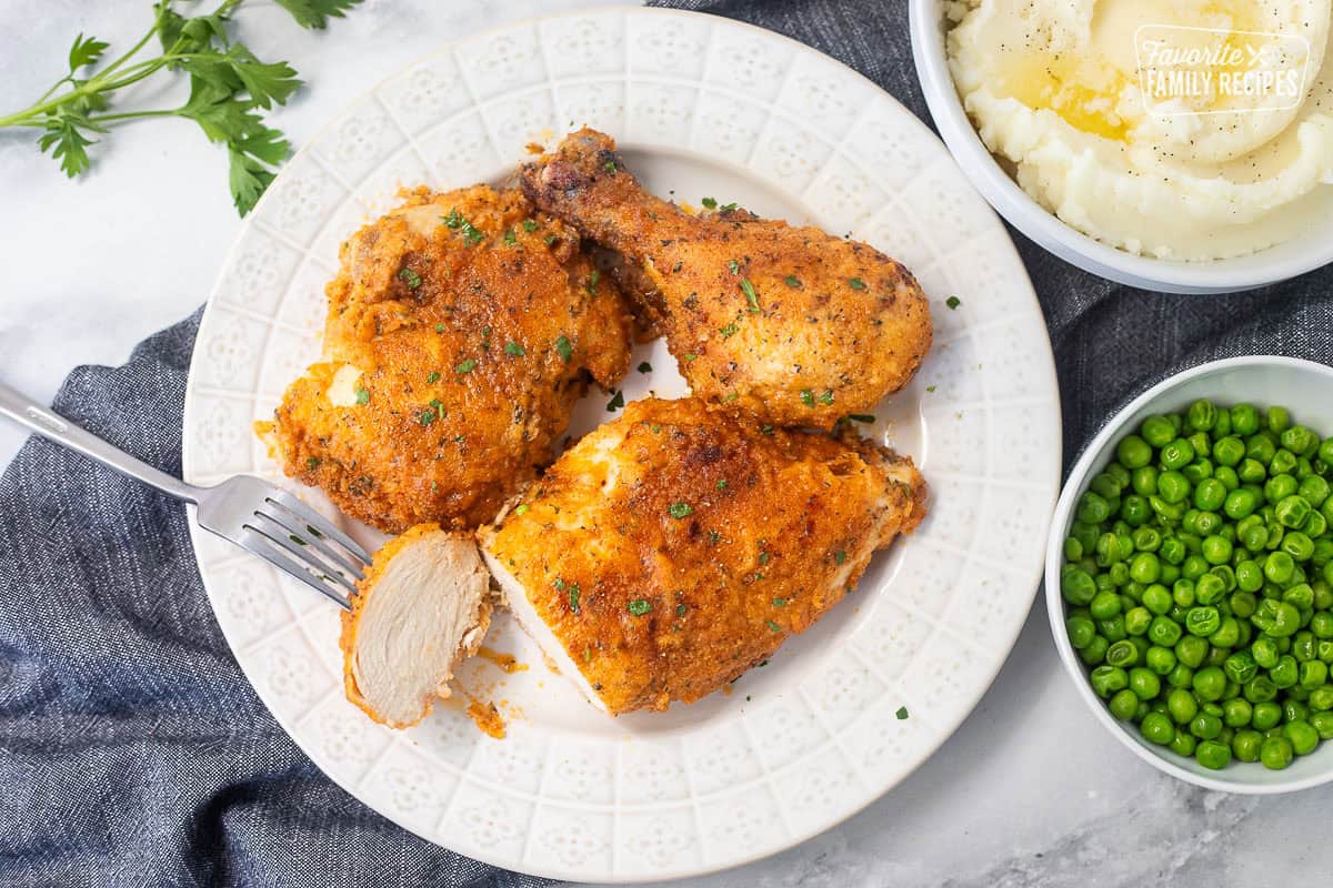 Cut piece of shake and bake chicken on a plate with a fork.