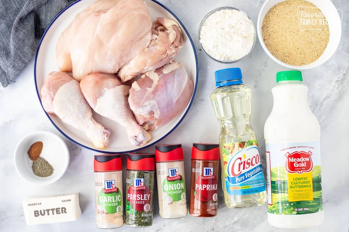 Ingredients to make shake and bake chicken including bread crumbs, buttermilk, vegetable oil, flour, paprika, onion powder, parsley flakes, garlic powder, butter, salt, pepper, cayenne pepper and assortment of chicken pieces.
