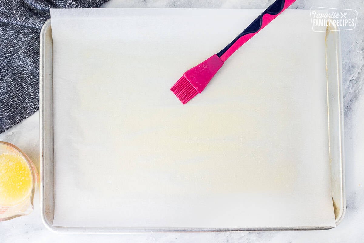 Sheet pan lined with parchment paper. Butter oil mixture spread on top with brush.