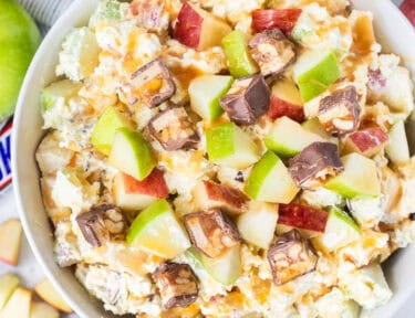 Bowl of Snickers salad topped with caramel sauce.