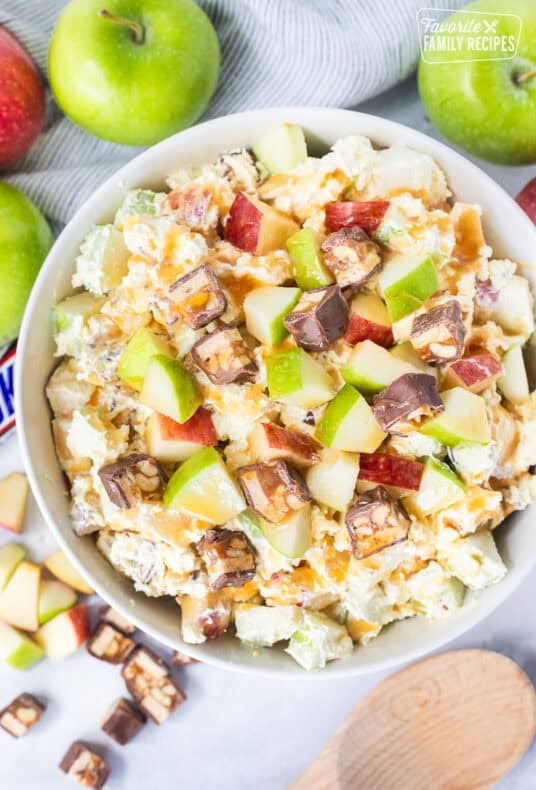 Bowl of Snickers salad topped with caramel sauce.