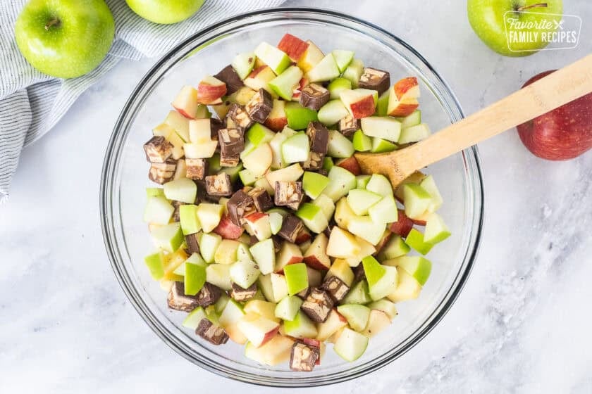 Glass bowl with combined apples and Snickers bars.