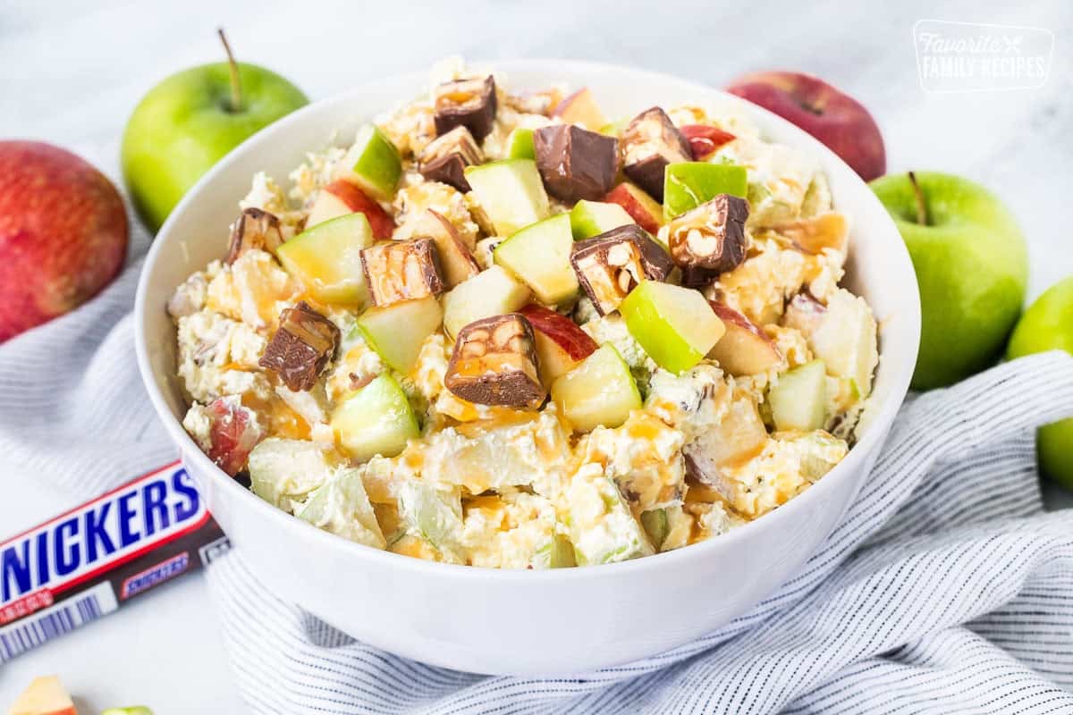 Bowl of Snickers salad topped with caramel sauce.