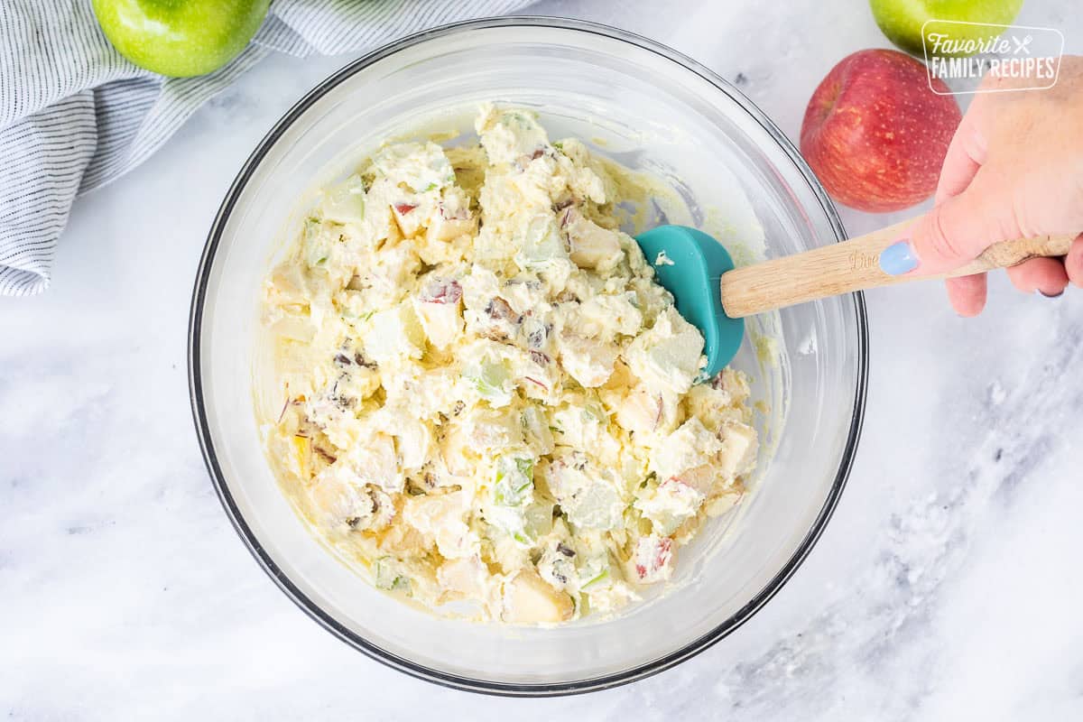 Stirring chopped apples into cool whip pudding mixture.