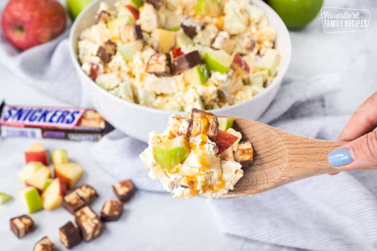 Bowl of Snickers salad topped with caramel sauce.