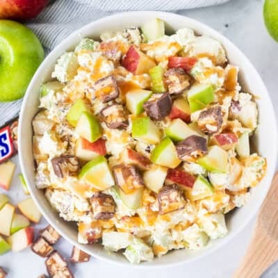 Bowl of Snickers salad topped with caramel sauce.
