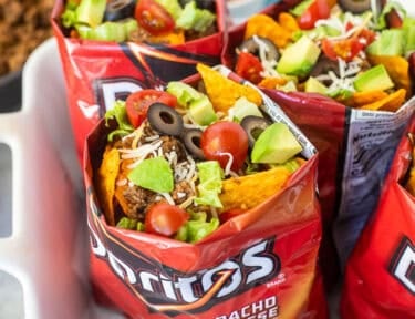 Bags of walking tacos with nacho cheese Doritos, seasoned ground beef, cheese, lettuce, tomatoes, olives and avocado.