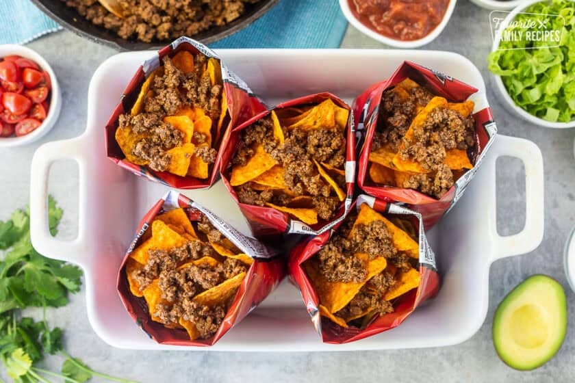 Ground beef on top of Doritos chips in bags.
