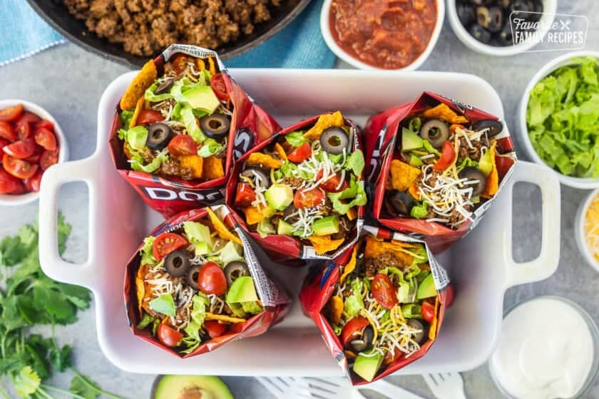 Walking tacos in small nacho cheese Doritos bags with chips, lettuce, avocado, olives, tomatoes and cheese.