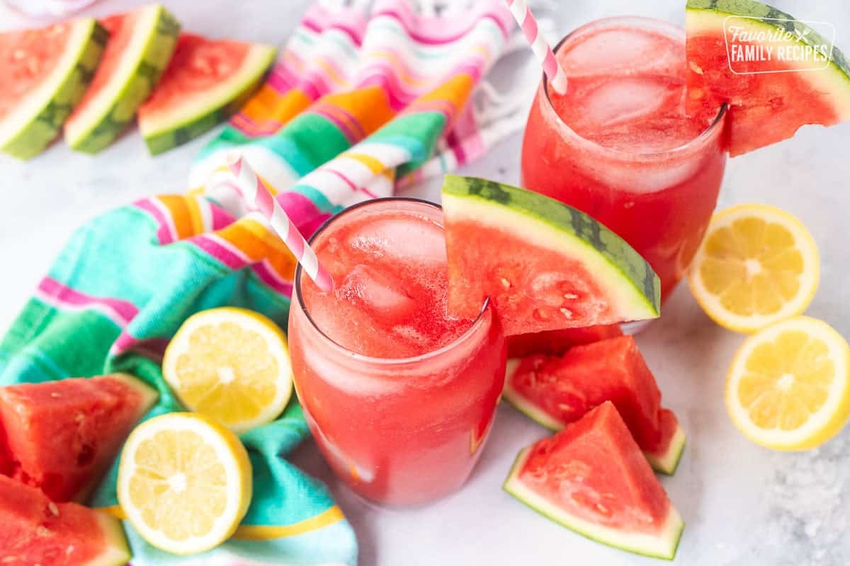 Glass of watermelon lemonade with a wedge of watermelon on the rim of the glass and a straw.