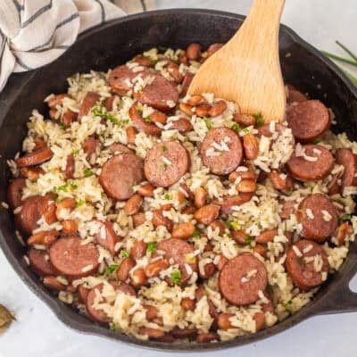 Skillet of Brazilian rice and beans with a wooden spoon.