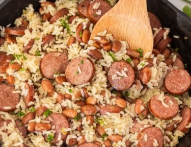 Skillet of Brazilian rice and beans with a wooden spoon.