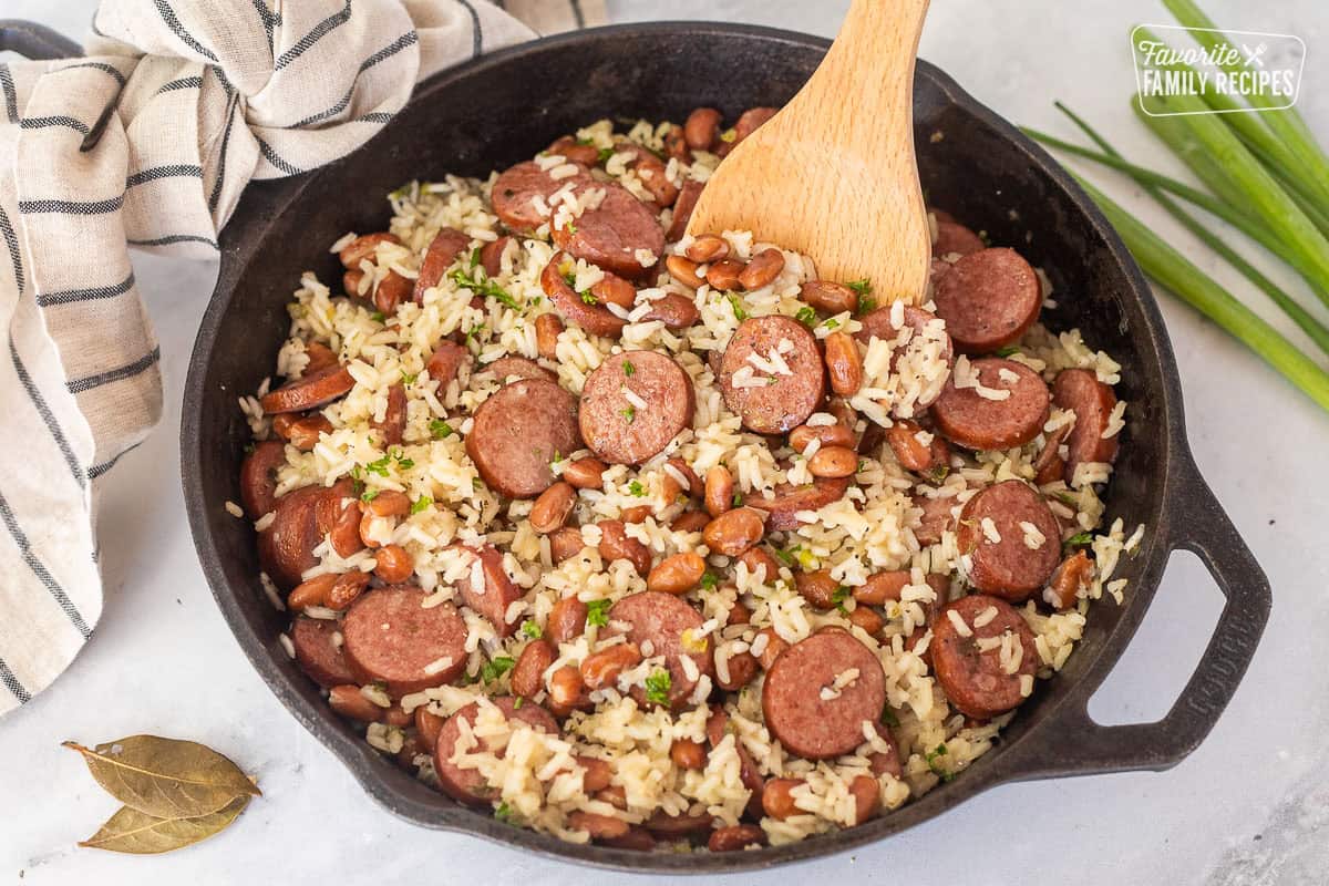 Skillet of Brazilian rice and beans with a wooden spoon.