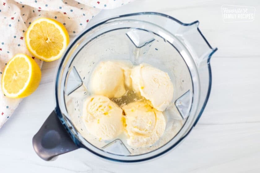 Blender with lemonade, vanilla ice cream scoops and lemon zest.