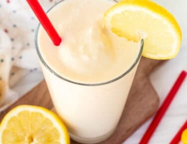 Chick Fil A Frosted Lemonade in a glass with a red straw and lemon slice on the side of the glass.