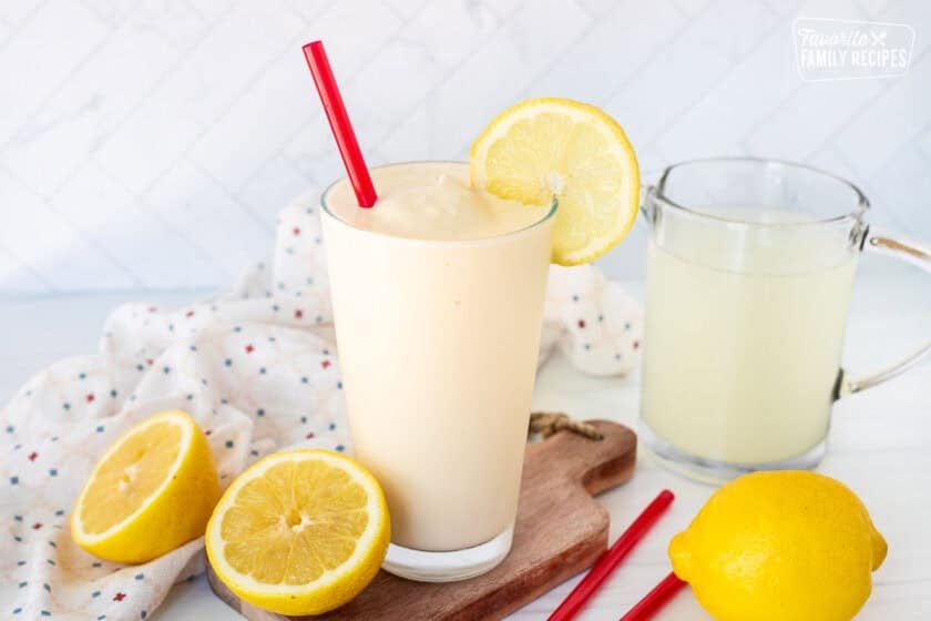 Glass of Chick Fil A Frosted Lemonade in a with a red straw and lemon slice on the rim of the glass.