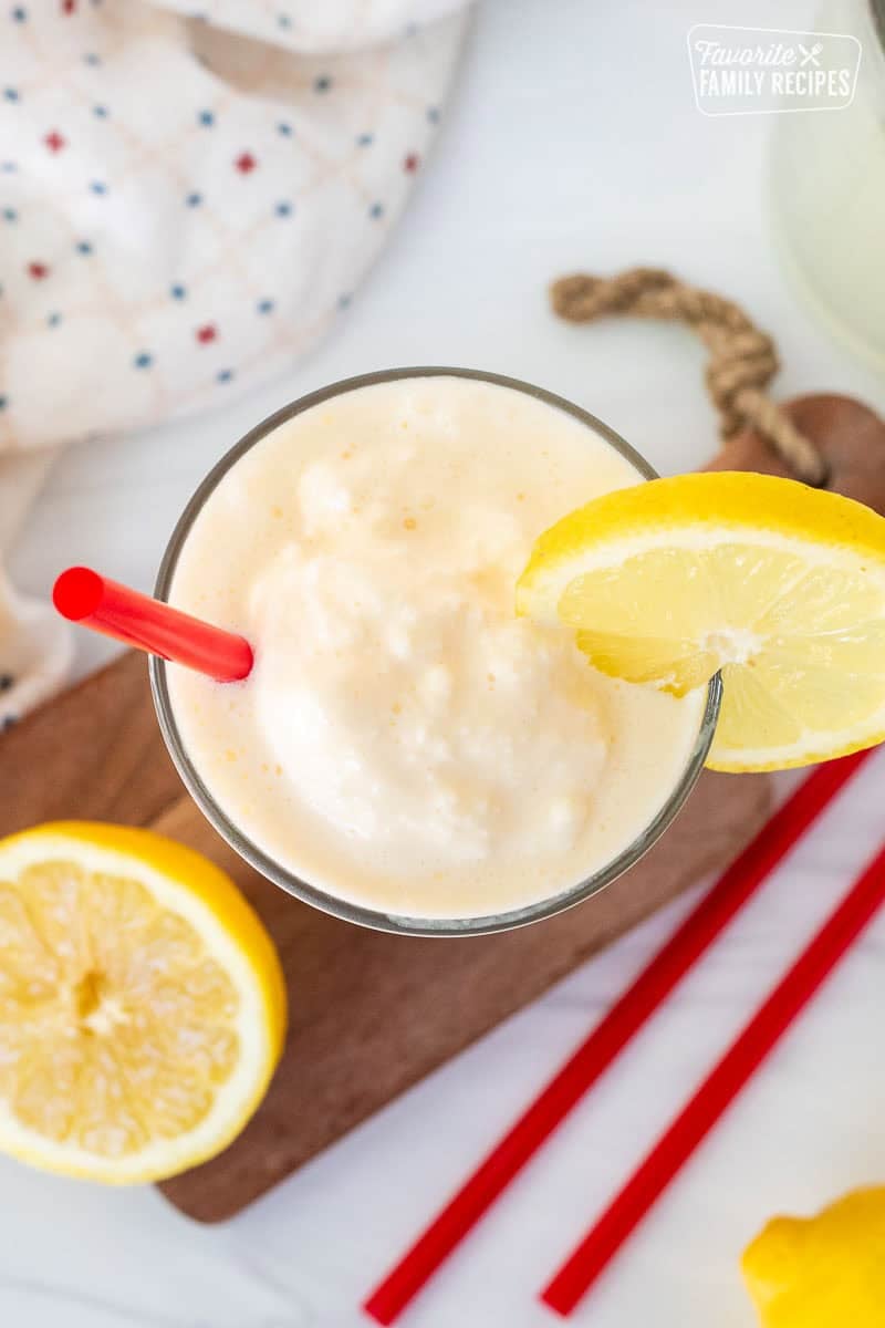 Chick Fil A Frosted Lemonade in a glass with a red straw and lemon slice on the side of the glass.