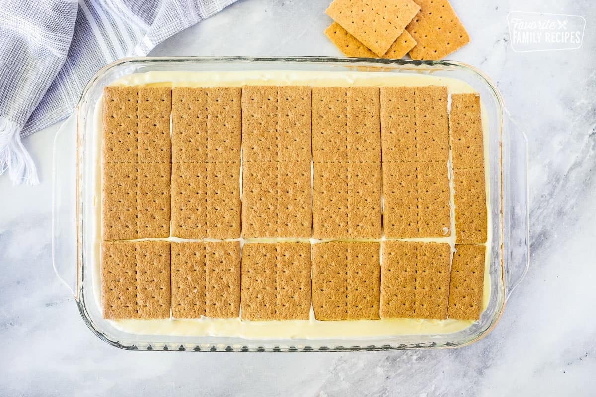 A second layer of graham crackers layered over sweet, creamy filling of a chocolate eclair cake
