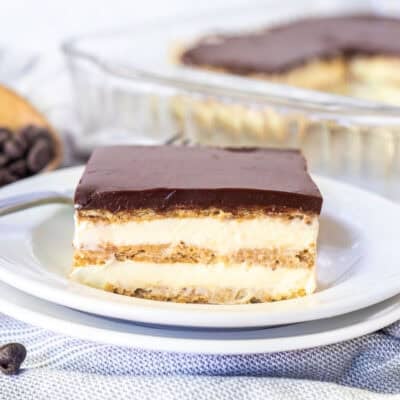 A slice of chocolate eclair cake showing layers of pudding and graham crackers and chocolate ganache topping