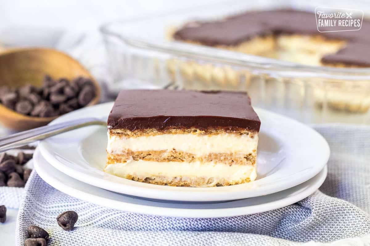 A slice of chocolate eclair cake showing layers of pudding and graham crackers and chocolate ganache topping