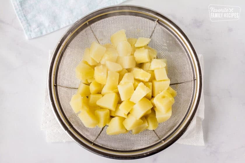 Cooked cube potatoes in colander for Corn Chowder with Bacon.