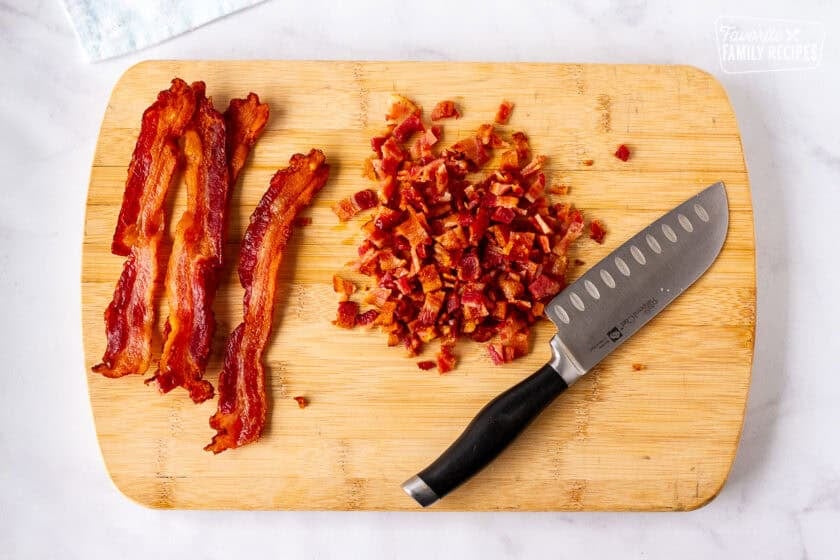 Cutting board with cut bacon and a knife.