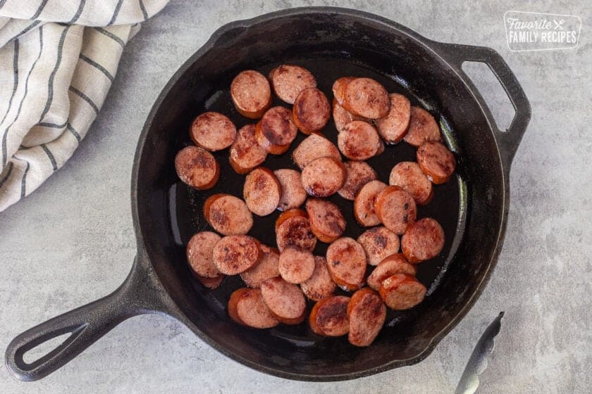 Skillet with sliced and browned smoked sausage.