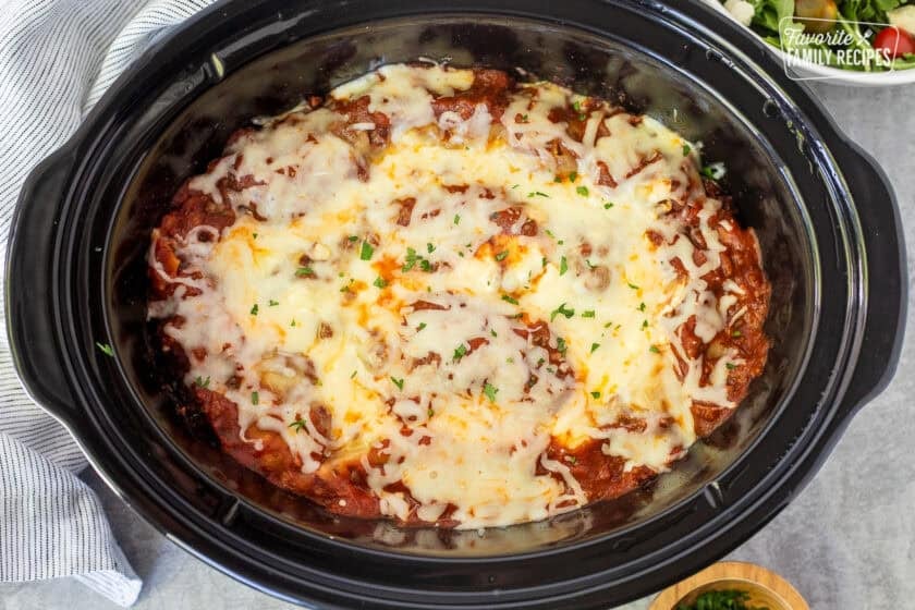 Crockpot lasagna in a crockpot garnished with parsley.