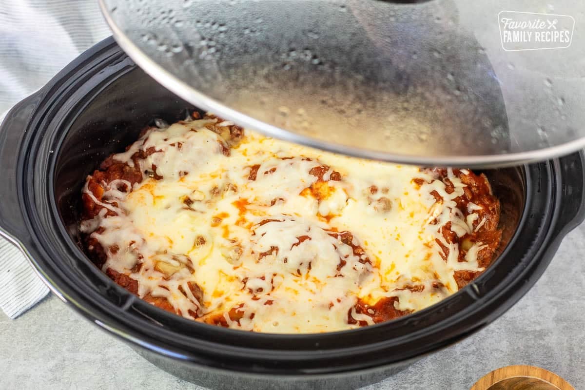 Lifting lid of cooked crockpot lasagna.