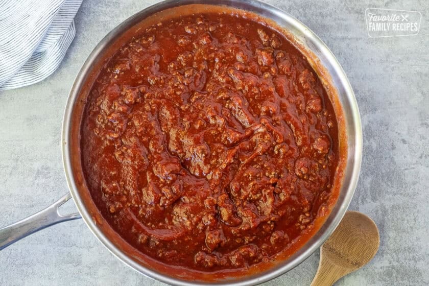 Skillet with red meat sauce and wooden spoon on the side.