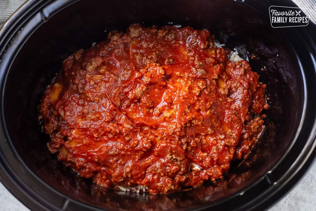 Red meat sauce on top of dry lasagna noodles in crockpot.