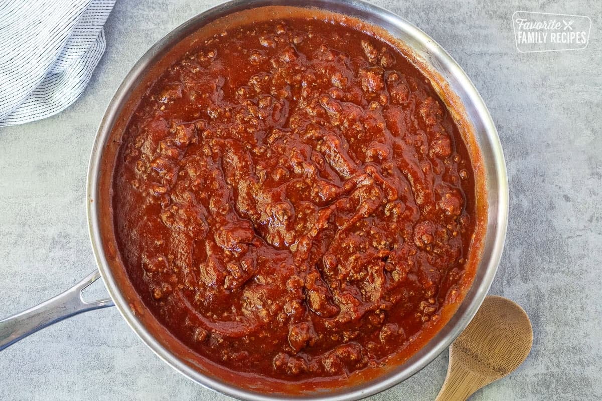 Skillet with red meat sauce and wooden spoon on the side.