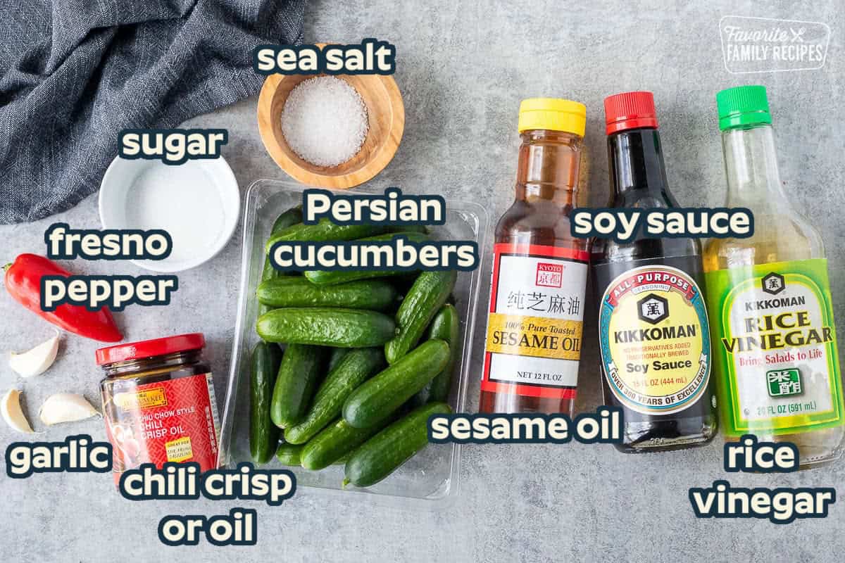 Ingredients to make Din Tai Fung Cucumber Salad including baby cucumbers, sesame oil, soy sauce, rice vinegar, chili crisp oil, salt, sugar, garlic and Fresno pepper.