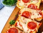 Cutting board with French bread pizza sliced.