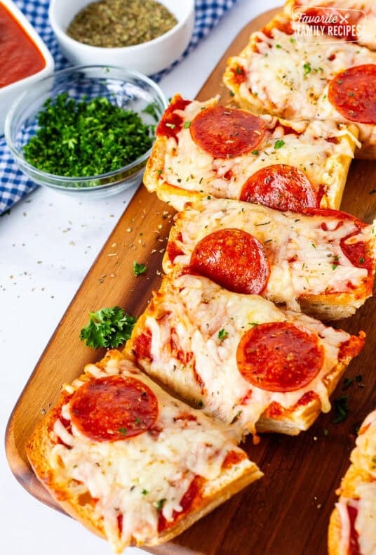 Cutting board with French bread pizza sliced.
