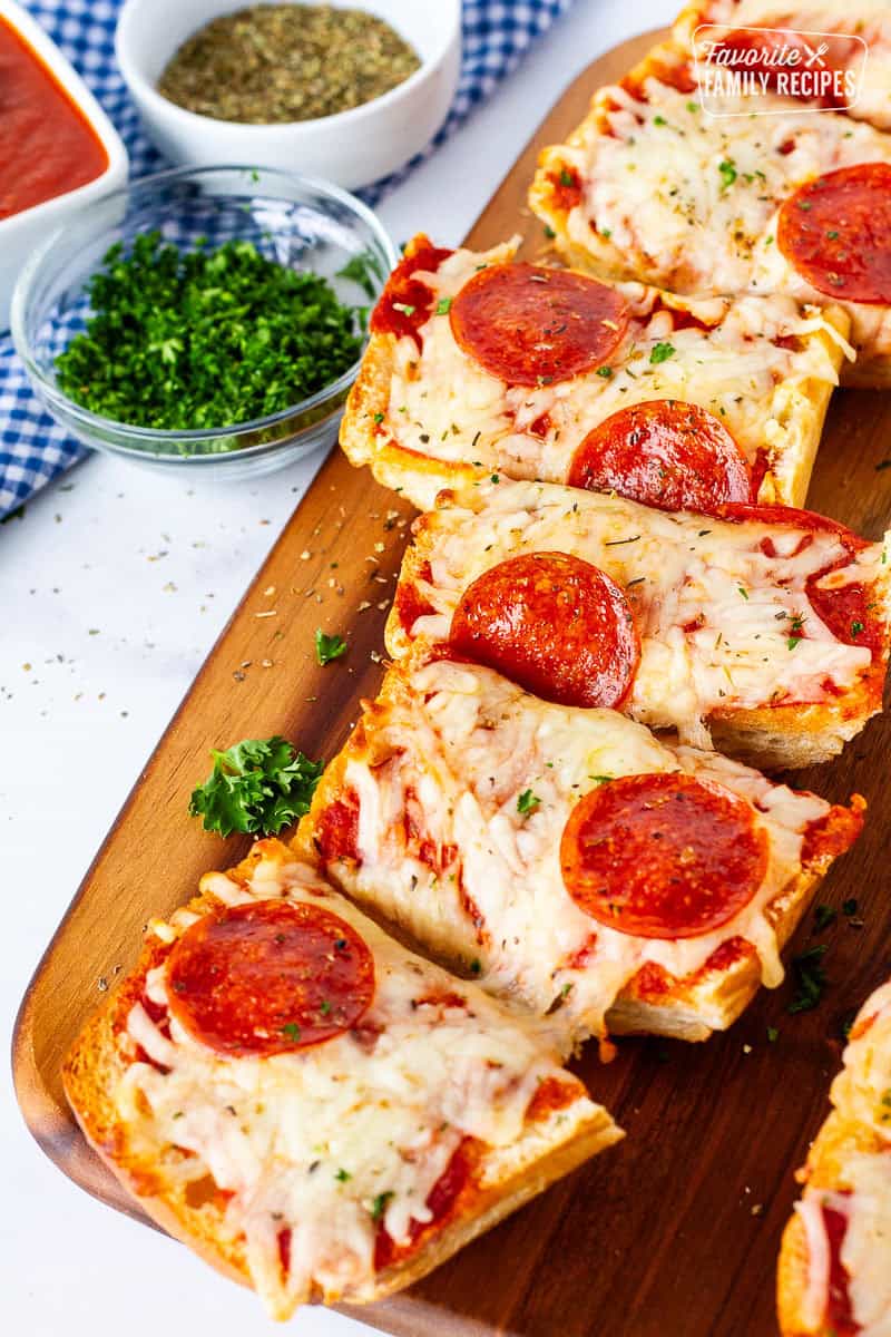 Cutting board with French bread pizza sliced.